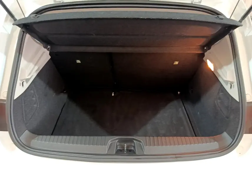 Coffre ouvert vu de face d'une Renault Clio Business Blue dCi 85 blanche, intérieur noir et éclairage latéral.