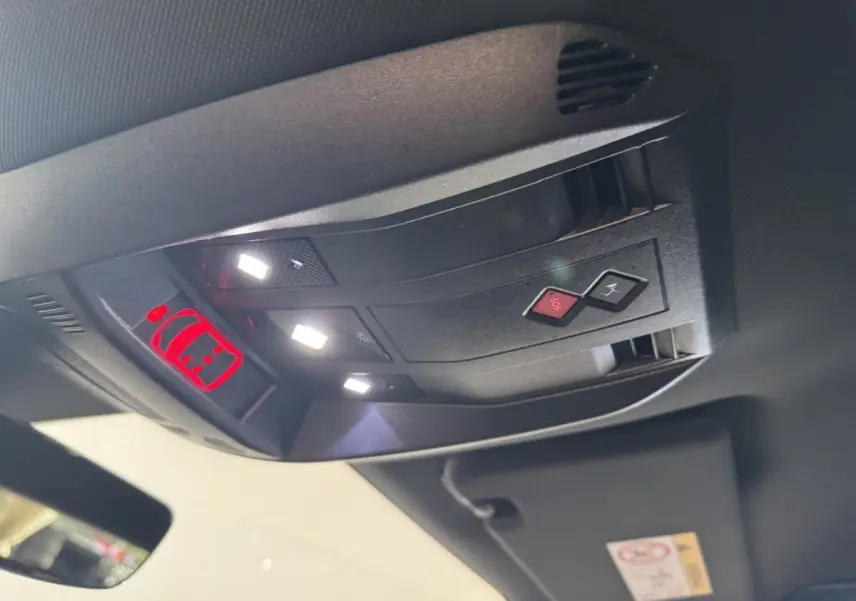 Vue intérieure en gros plan du plafonnier avec boutons SOS et éclairage, dans un DS7 Crossback gris foncé.