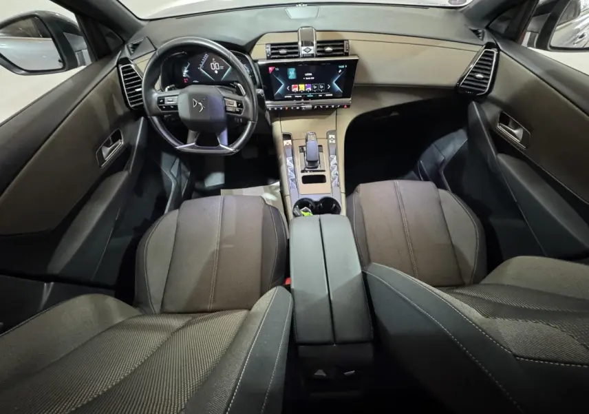 Vue intérieure avant du DS7 Crossback E-TENSE 225 Bastille+ montrant le tableau de bord noir avec écran tactile central et volant cuir.