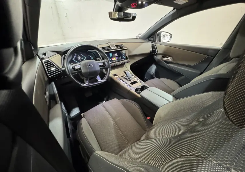 Vue intérieure avant droite du DS7 Crossback E-TENSE 225 Bastille+ montrant le tableau de bord et les sièges en tissu gris.