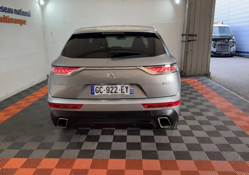 Vue arrière du DS7 Crossback E-TENSE gris foncé avec feux LED allumés et double sortie d’échappement carrée.