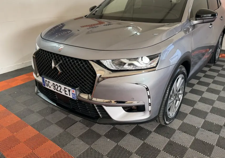 Vue 3/4 avant droit d’un DS7 Crossback E-TENSE gris foncé avec calandre noire et feux LED allumés.
