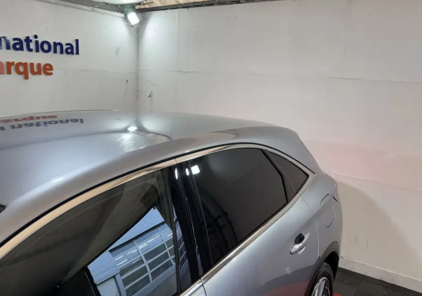 Vue 3/4 arrière côté droit du DS7 Crossback gris foncé avec vitres teintées et lignes de toit élancées.