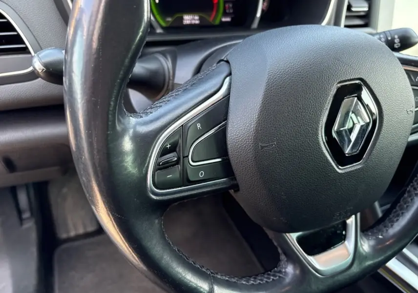 Gros plan sur le volant cuir noir de la Renault Mégane Intens 2020 avec commandes intégrées et logo central brillant.