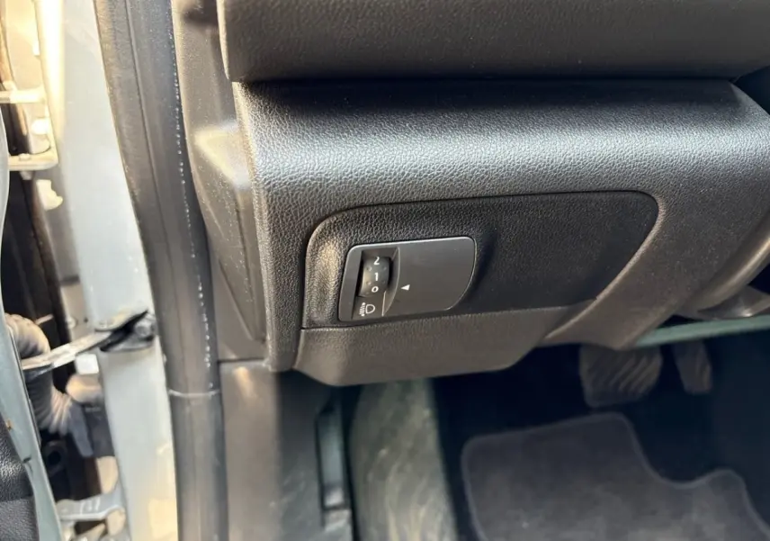 Gros plan sur le réglage des phares situé sous le tableau de bord côté conducteur d’une Renault Mégane 2020 gris clair.