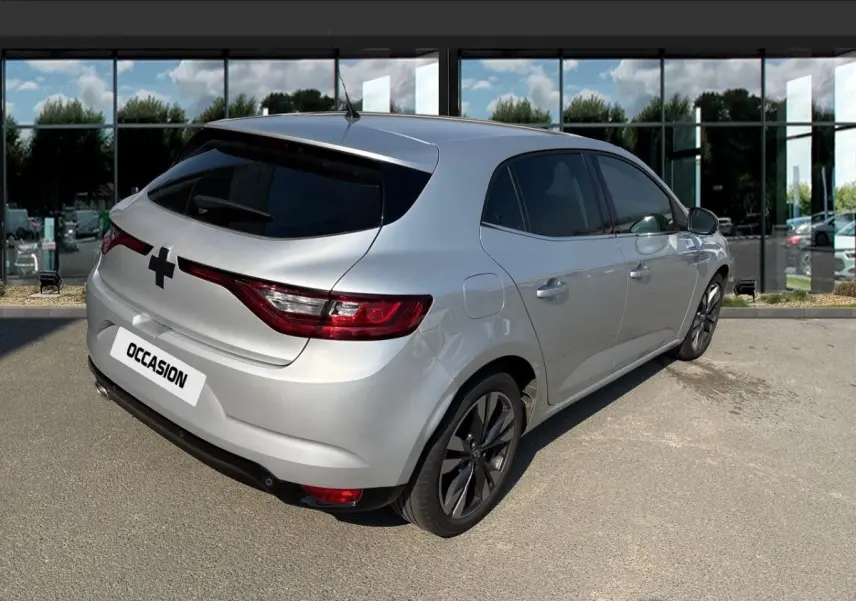 Vue 3/4 arrière droite d'une Renault Mégane Intens Blue dCi 115 gris clair avec jantes alliage et vitres teintées.