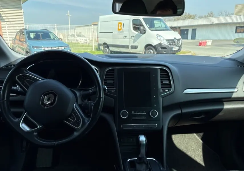 Vue intérieure avant du tableau de bord et volant cuir noir de la Renault Mégane Intens 2020 avec écran tactile central éteint.