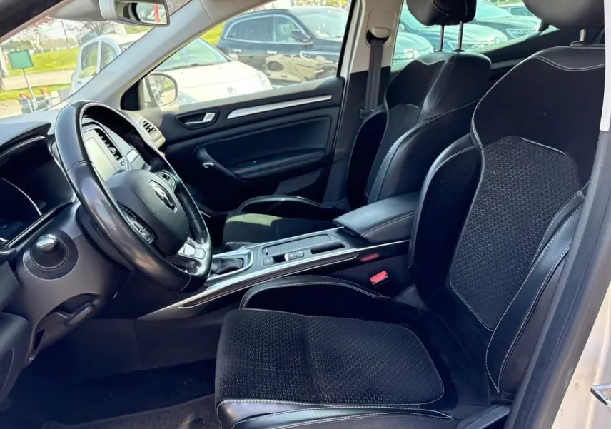 Vue intérieure côté conducteur de la Renault Mégane Intens 2020, sièges noirs avec surpiqûres blanches et volant cuir.