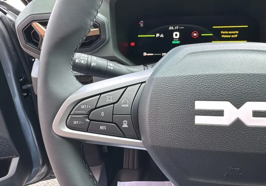 Gros plan sur le volant cuir gris et les commandes multifonctions du Dacia Bigster Hybrid 155 Extreme Plus, intérieur gris schiste.