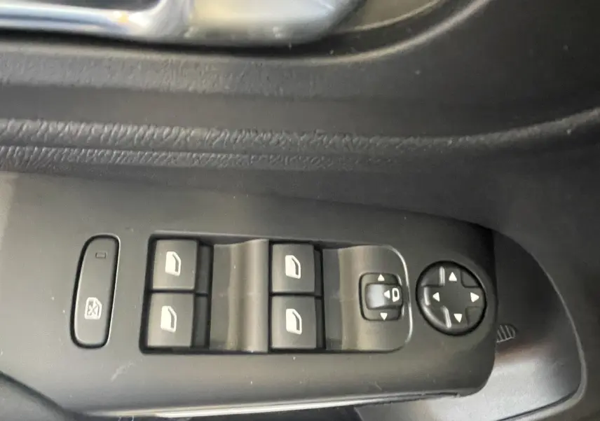 Gros plan sur les commandes de lève-vitres et réglage des rétroviseurs côté conducteur d'une Citroën C5 Aircross bleu foncé.