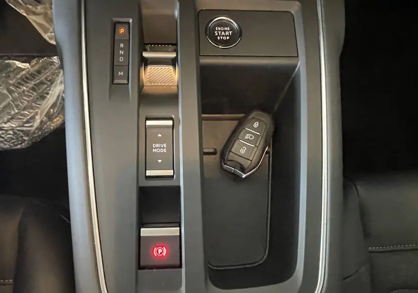 Vue rapprochée de la console centrale du Citroën C5 Aircross hybride 2025 avec clé et boutons de démarrage et mode de conduite.