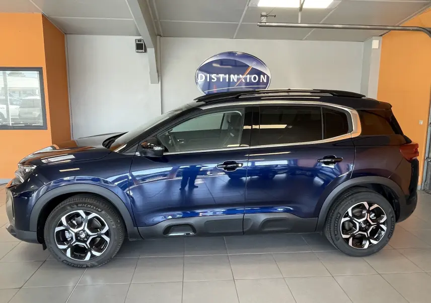 Profil latéral droit d’un Citroën C5 Aircross hybride 2025 bleu foncé avec jantes alliage biton 18 pouces et vitres arrière surteintées.