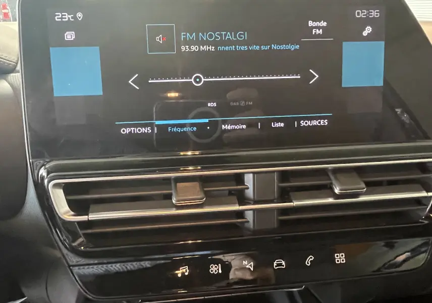 Écran tactile central de la Citroën C5 Aircross hybride 2025 affichant la radio FM Nostalgie, avec commandes climatisation et ventilation en dessous.