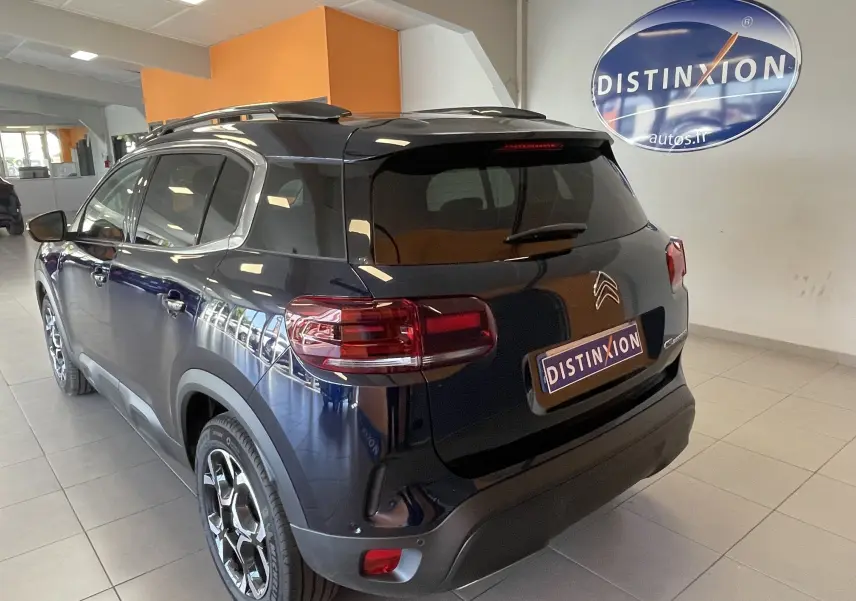 Vue 3/4 arrière droite du Citroën C5 Aircross hybride 2025 en bleu foncé avec jantes alliage biton et vitres surteintées.