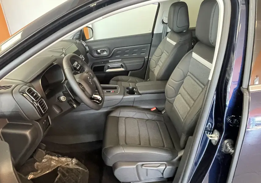 Vue intérieure côté conducteur du Citroën C5 Aircross hybride bleu foncé, avec sièges tissu/TEP gris et volant cuir.