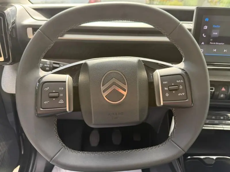 Vue rapprochée du volant noir de la Citroën C3 2025 avec commandes intégrées et logo chromé central.