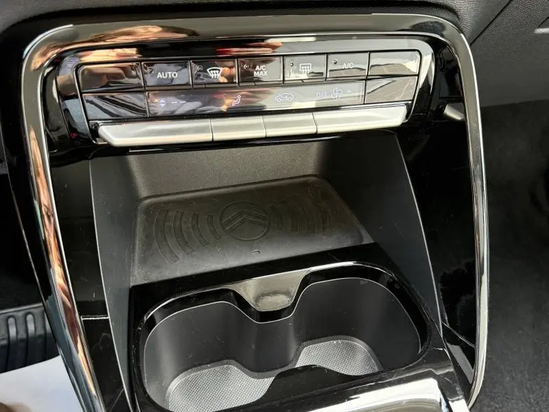 Gros plan sur la console centrale noire de la Citroën C3 2025, avec commandes climatisation et espace de rangement.