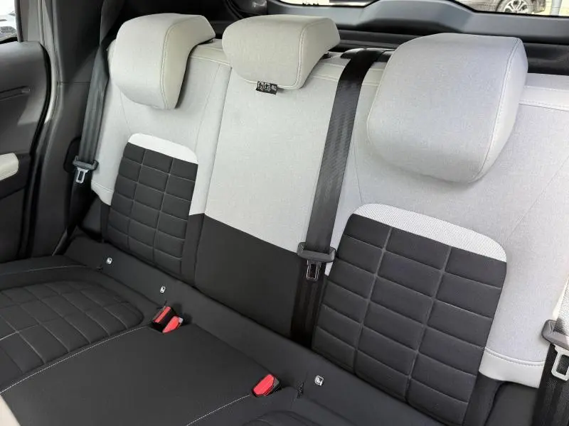 Vue intérieure de la banquette arrière bicolore noir et gris clair de la Citroën C3 1.2 Turbo 2025, avec ceintures et appuie-têtes.