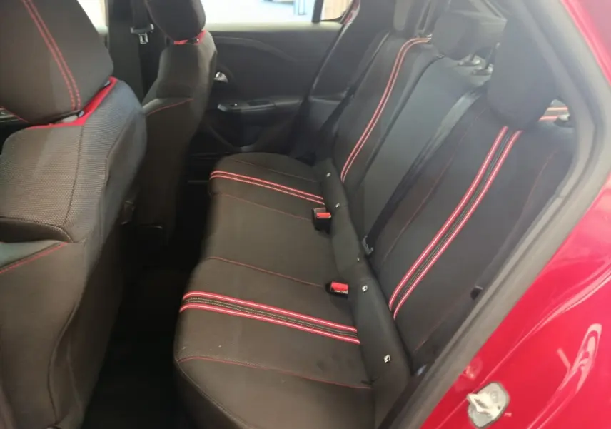 Vue intérieure côté arrière droit de l’Opel Corsa rouge 2023, banquette noire avec surpiqûres rouges visibles.