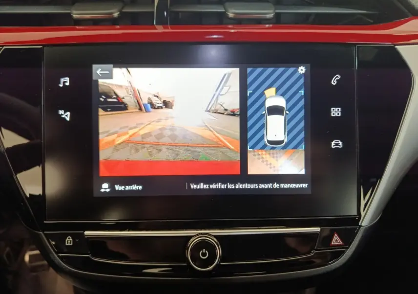 Écran tactile central de l’Opel Corsa rouge 2023 montrant la caméra de recul et l’aide au stationnement arrière.