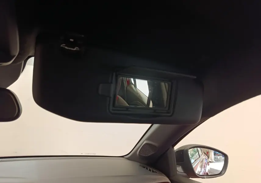 Vue intérieure côté conducteur de l'Opel Corsa rouge 2023, avec miroir de soleil ouvert et rétroviseur latéral visible.