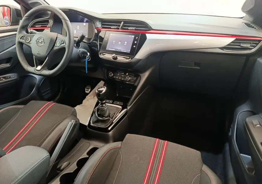 Vue intérieure côté conducteur de l’Opel Corsa 1.2 Turbo 2023, volant cuir, console centrale avec écran tactile et surpiqûres rouges.