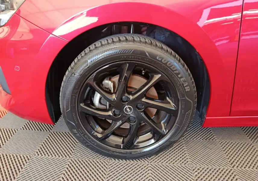 Gros plan sur la roue avant gauche noire d’une Opel Corsa rouge 2023 avec jante en alliage et pneu Goodyear.