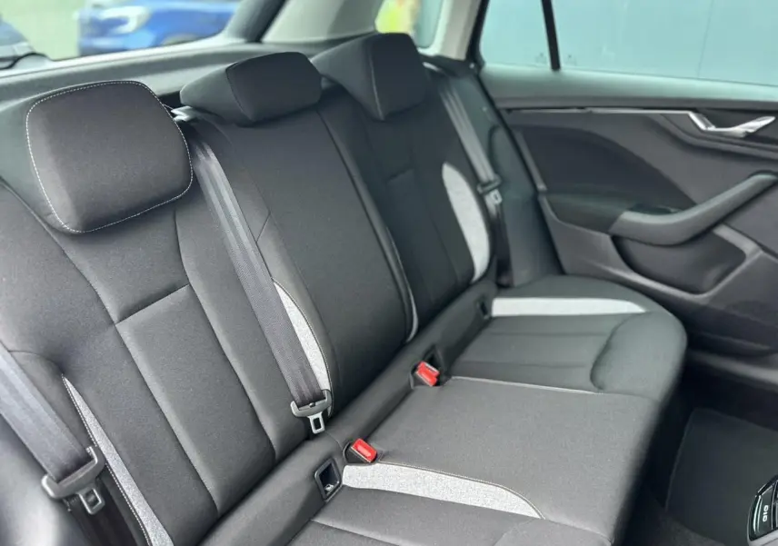 Vue intérieure du siège arrière droit du Skoda Kamiq 2025 noir Magic avec tissu gris clair et ceintures visibles.