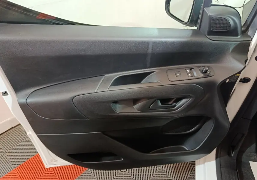 Vue rapprochée de la porte côté conducteur noire du Citroën Berlingo blanc avec commandes électriques des vitres.