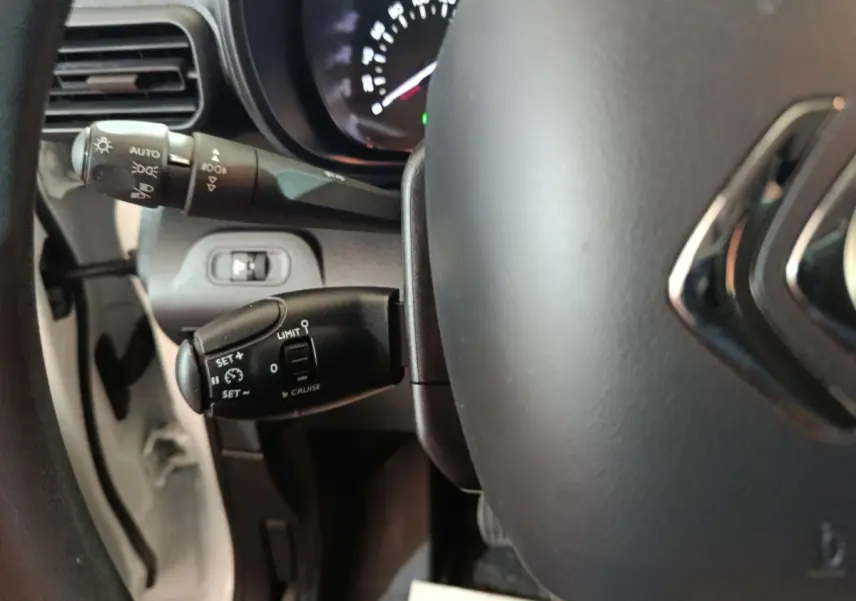 Gros plan sur le volant et les commandes de régulateur de vitesse du Citroën Berlingo blanc, version 2021.