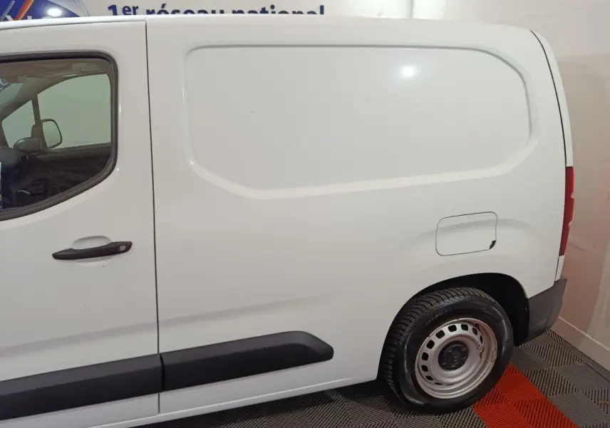 Vue de profil côté droit d'un utilitaire Citroën Berlingo blanc avec porte latérale pleine et jante acier.