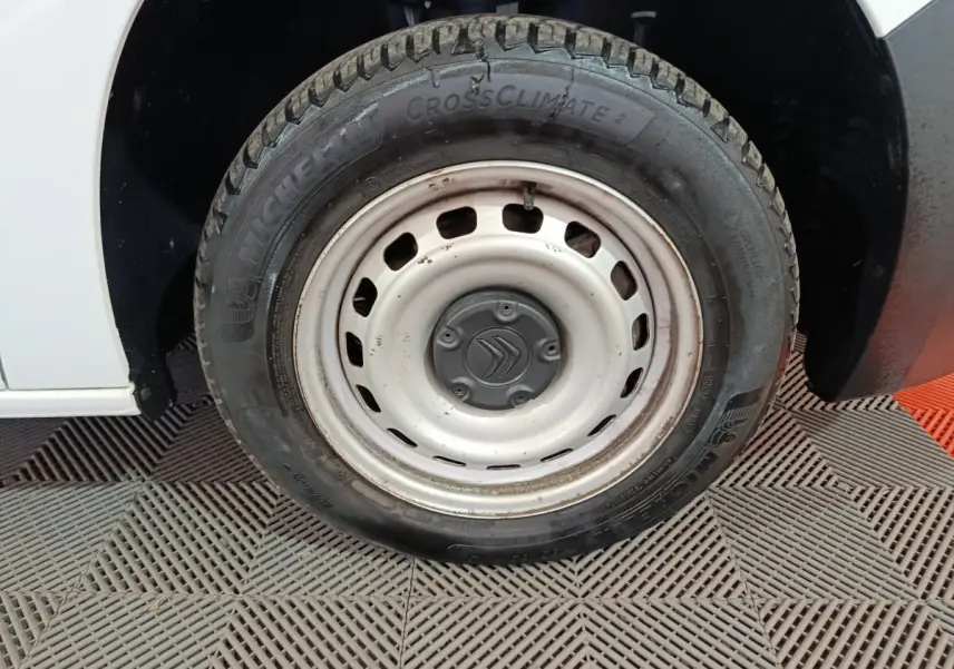 Gros plan sur la roue avant gauche blanche en acier d'un Citroën Berlingo blanc 2021, pneu Michelin CrossClimate.