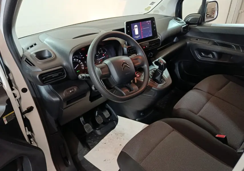 Intérieur du Citroën Berlingo blanc 2021, vue côté conducteur, tableau de bord avec écran tactile et volant noir.