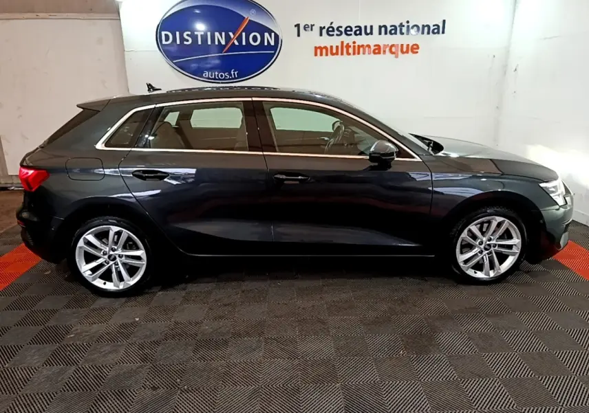 Vue latérale droite d'une Audi A3 35 TFSI gris foncé stationnée en intérieur avec jantes alliage et vitres teintées.
