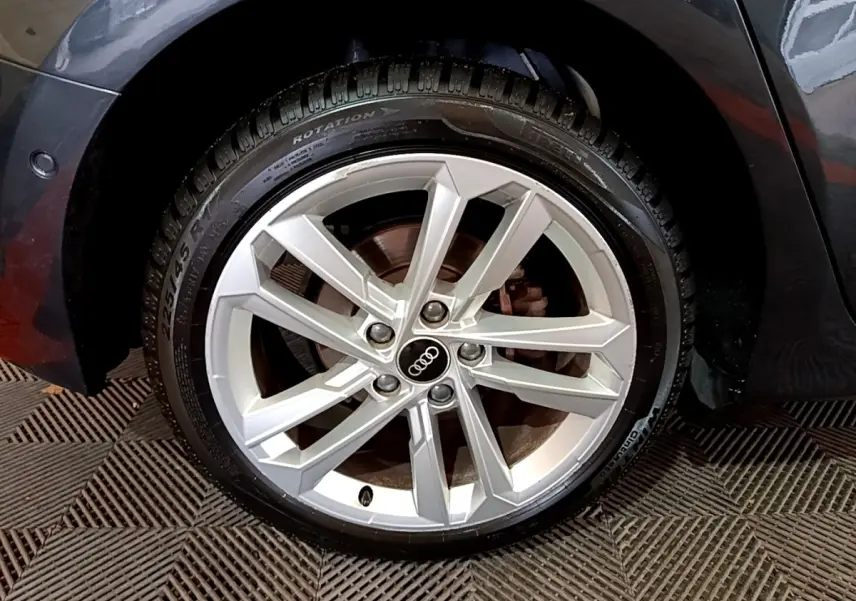 Gros plan sur la roue avant droite d'une Audi A3 gris foncé, mettant en valeur la jante alliage à cinq doubles branches.