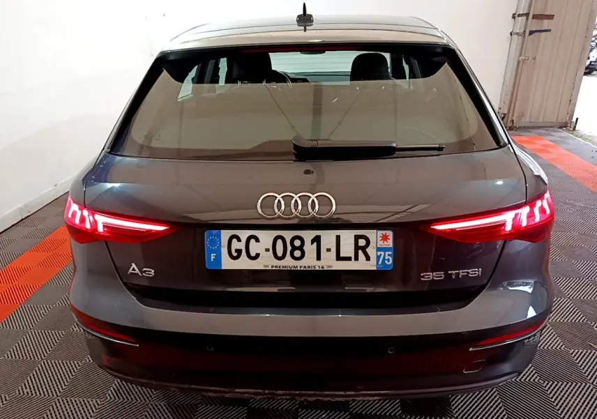 Vue arrière d'une Audi A3 35 TFSI gris foncé avec feux LED allumés dans un garage fermé.