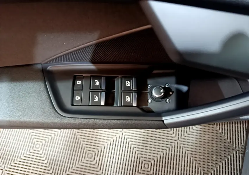 Vue rapprochée des commandes des vitres et rétroviseurs sur la porte côté conducteur d'une Audi A3 gris foncé 2021.