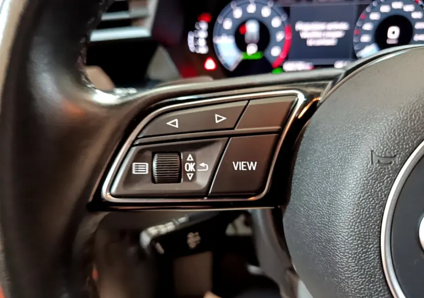 Gros plan sur les commandes gauche du volant cuir noir d'une Audi A3 35 TFSI 150 MHEV Business Line 2021.