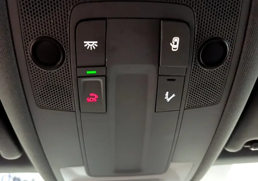 Vue en contre-plongée du panneau de commandes au plafond intérieur gris foncé de l'Audi A3 avec bouton SOS éclairé en rouge.