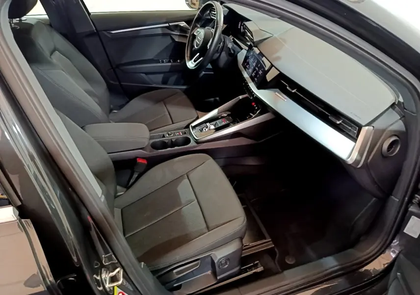 Vue intérieure côté conducteur de l'Audi A3 35 TFSI gris foncé, avec tableau de bord moderne et écran tactile central.