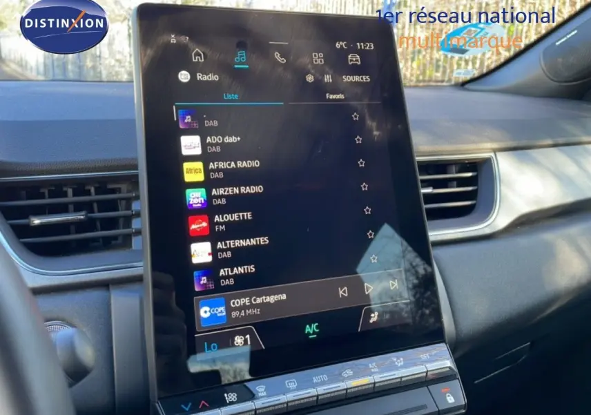 Vue rapprochée de l’écran tactile central du Renault Captur 2025, affichant les stations radio numériques, avec tableau de bord gris noir en arrière-plan.