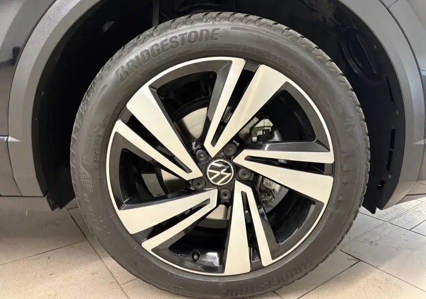 Gros plan sur la roue avant droite noire intense du Volkswagen T-Roc 1.5 TSI 150 DSG7 R-Line Edition avec jante alliage bicolore.