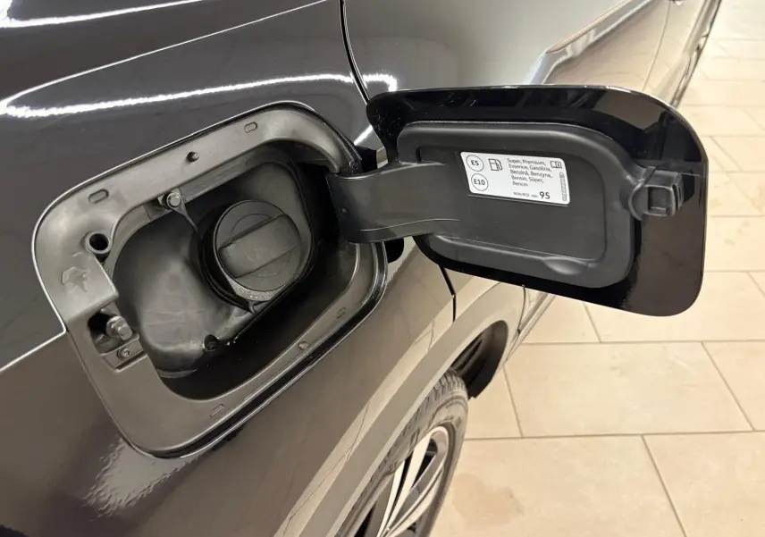 Bouchon de réservoir essence ouvert côté gauche sur Volkswagen T-Roc noir intense, vue rapprochée en intérieur.