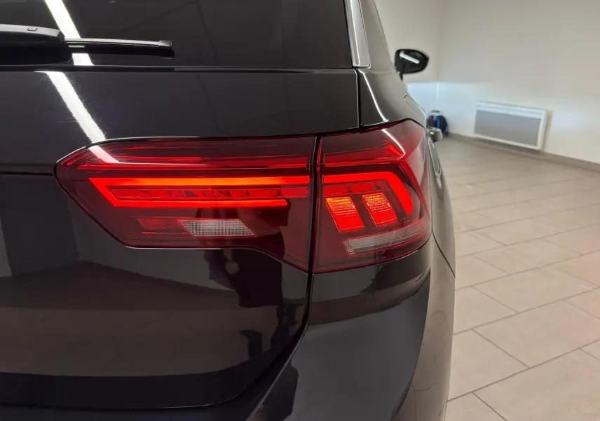 Gros plan sur le feu arrière droit d’un Volkswagen T-Roc noir intense, mettant en valeur ses lignes lumineuses modernes.