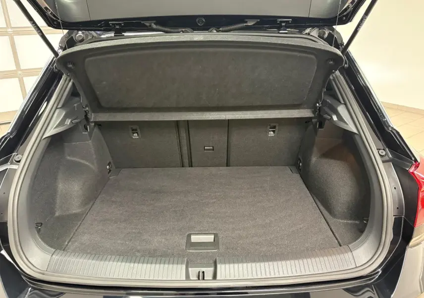 Coffre ouvert du Volkswagen T-Roc noir intense, vue arrière montrant l’espace de chargement vide et la moquette grise.