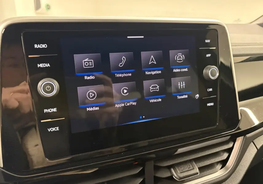 Écran tactile central du Volkswagen T-Roc 2025 affichant les options radio, téléphone, navigation et aides à la conduite.