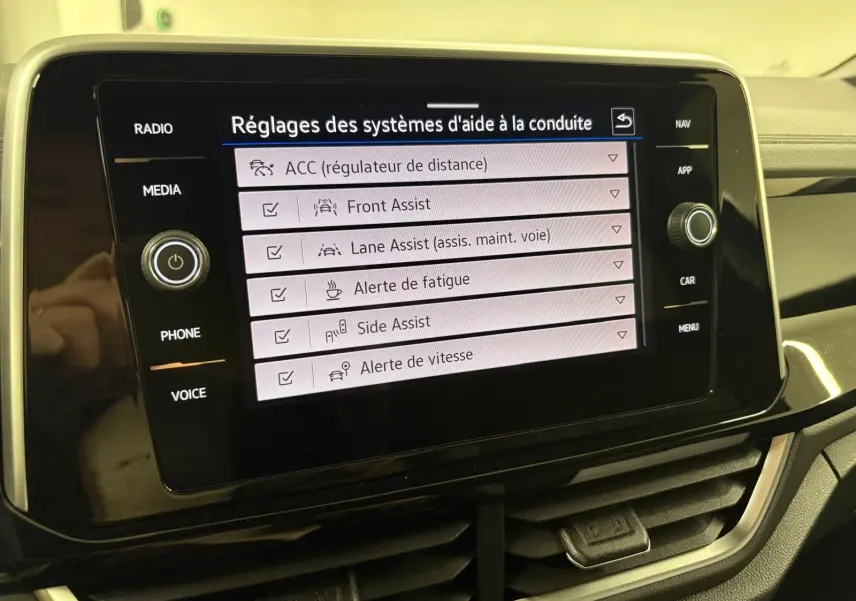 Écran tactile central du Volkswagen T-Roc 2025 affichant les réglages des aides à la conduite, vue rapprochée intérieure.
