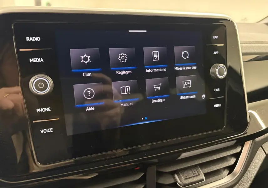 Écran tactile central du Volkswagen T-Roc 2025 affichant le menu principal avec options clim, réglages et boutique.