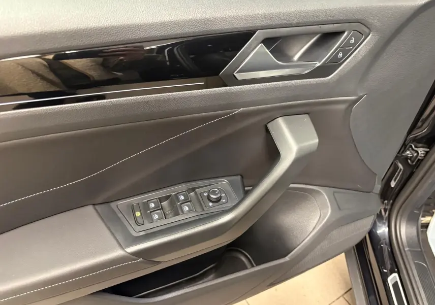 Gros plan sur la porte avant gauche noire du Volkswagen T-Roc 1.5 TSI R-Line avec commandes de vitres et verrouillage.