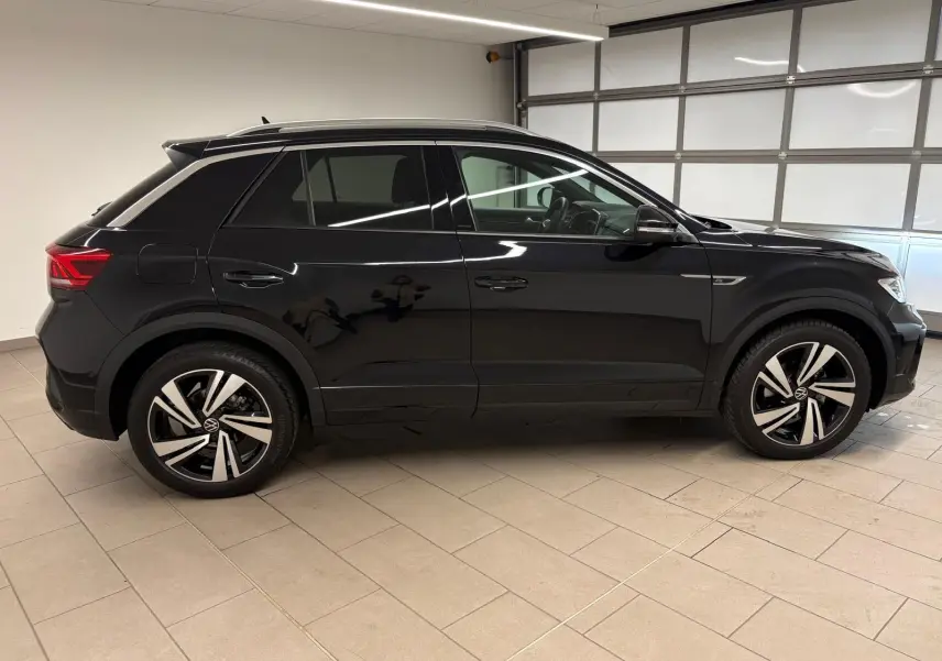 Profil côté gauche du Volkswagen T-Roc noir intense 2025 en finition R-Line, avec jantes alliage distinctives.